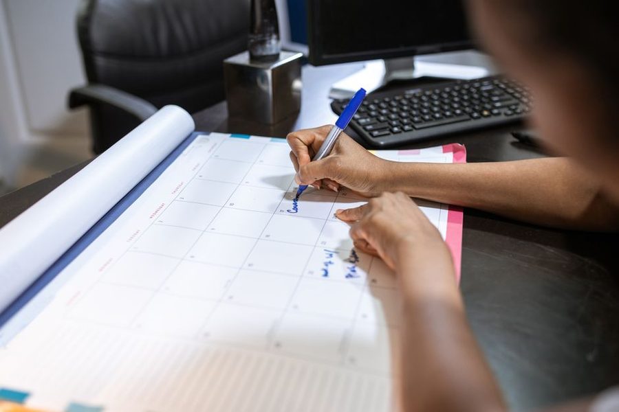 Mulher marcando uma data em um calendário de mesa no escritório