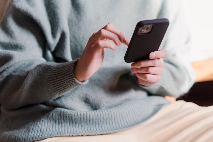 Pessoa sentada no sofá conferindo o pedido pelo celular